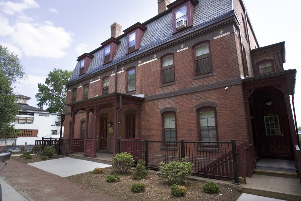 a red brick house with a front porch and a sidewalk