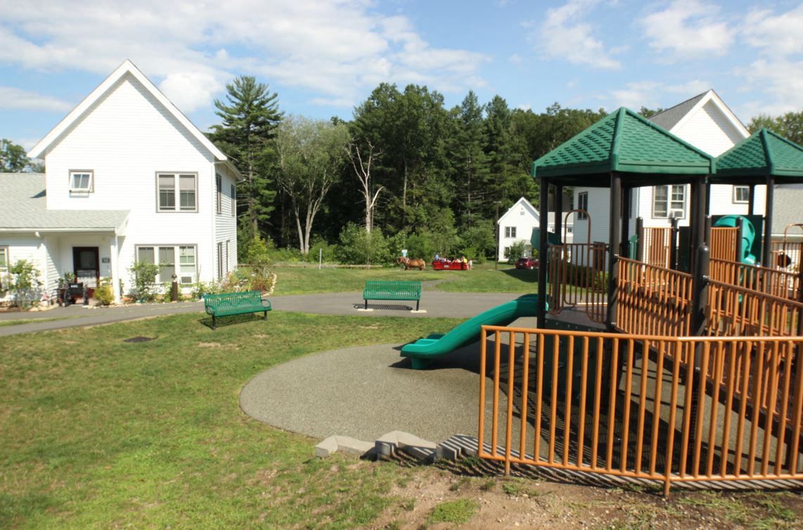 a playground with benches and a swing set in front of houses