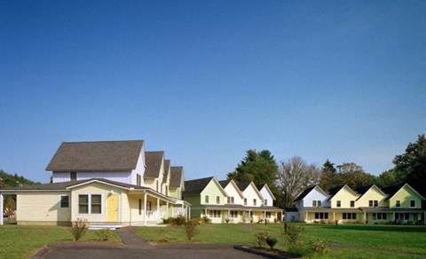 a row of houses in a field with a blue sky