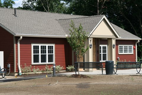 a small red house with a bench in front of it