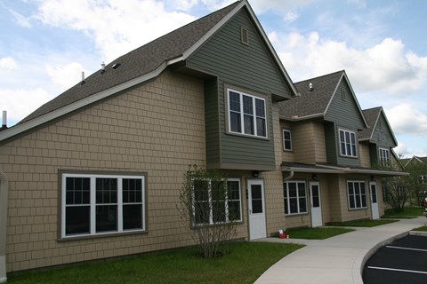 a green house with a sidewalk in front of it