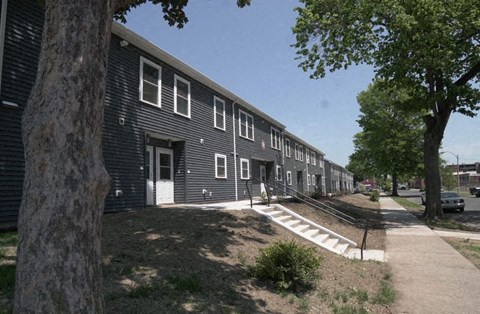a row of black buildings with trees and a sidewalk
