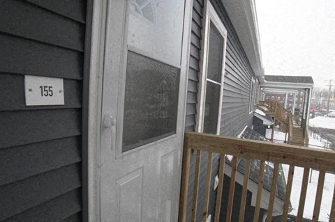 a front door of a house with a balcony in the snow