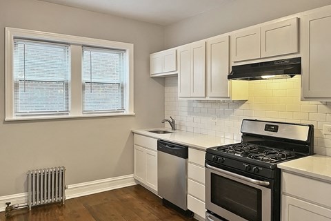 A kitchen with a stove, dishwasher, and window.