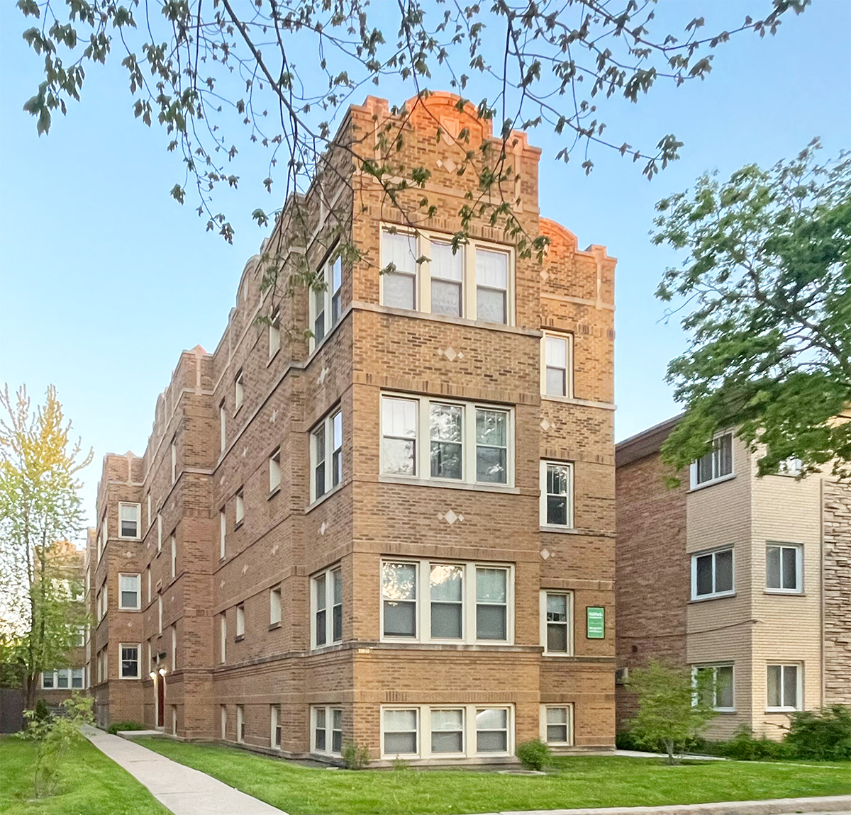 A tall brick apartment building with a green lawn in front.