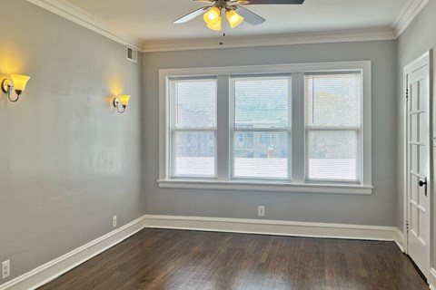 A room with a ceiling fan and a window with blinds.