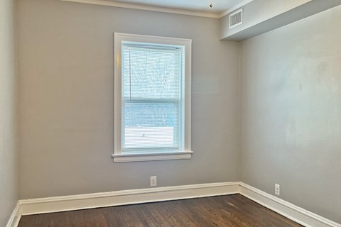 A room with a window and wooden flooring.