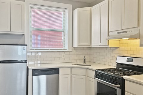 A kitchen with white cabinets and a black stove top oven.