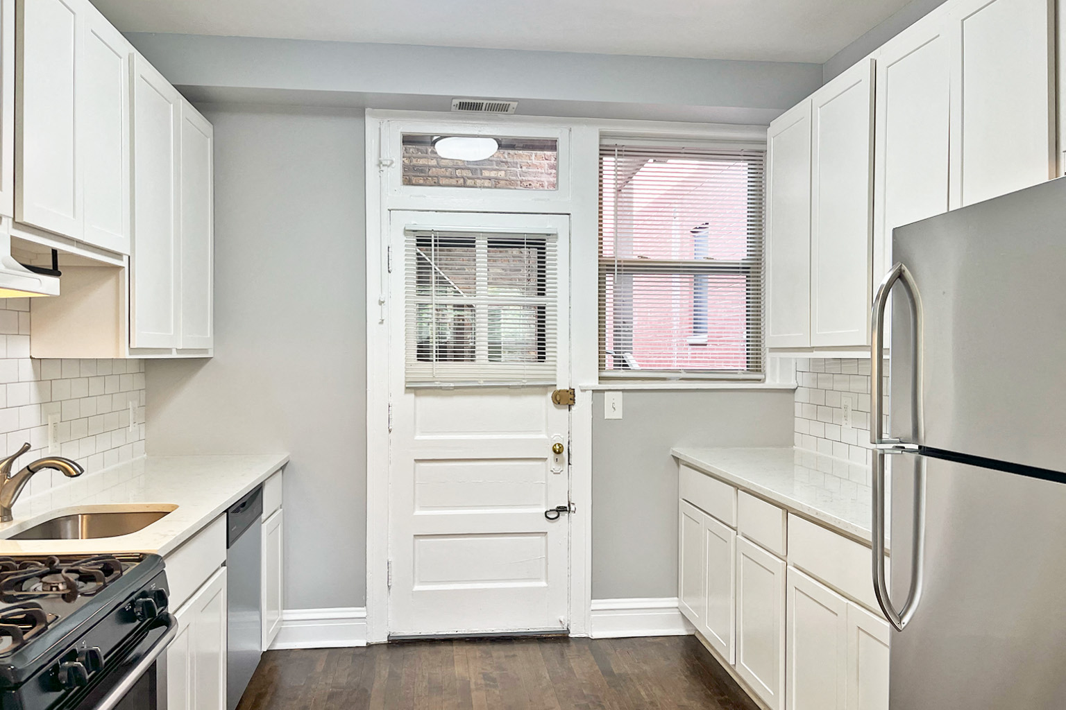 A white kitchen with a black stove top oven.