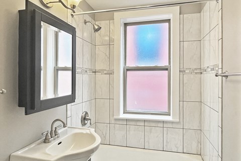 A bathroom with a white sink and a window with a rainbow reflection.