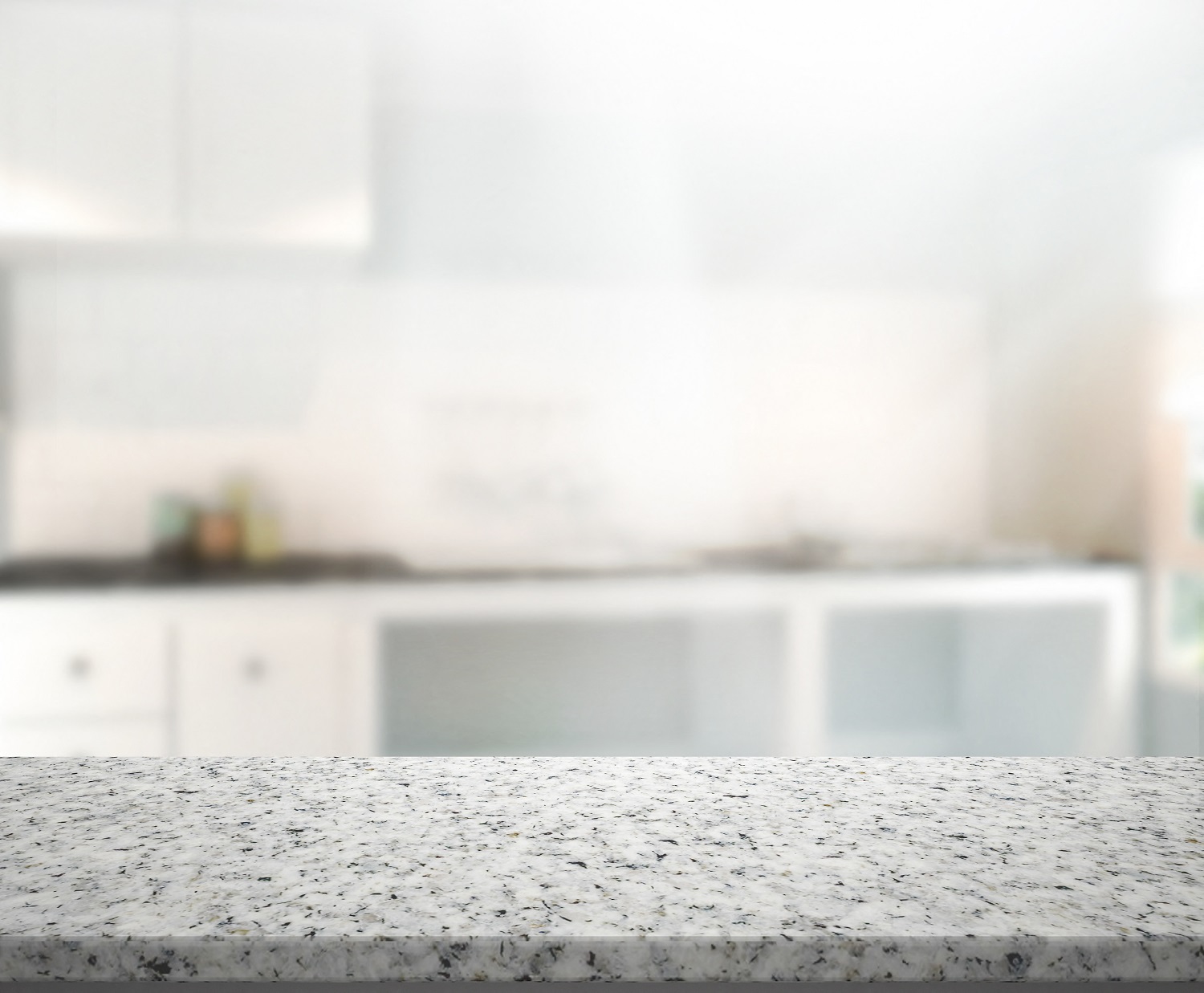 A kitchen with white cabinets and a marble countertop.