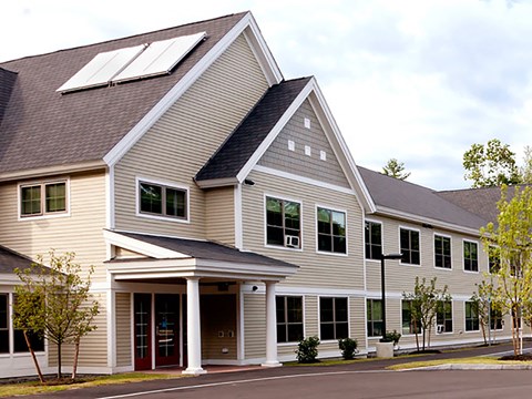 A modern house with a brown roof and a red door.