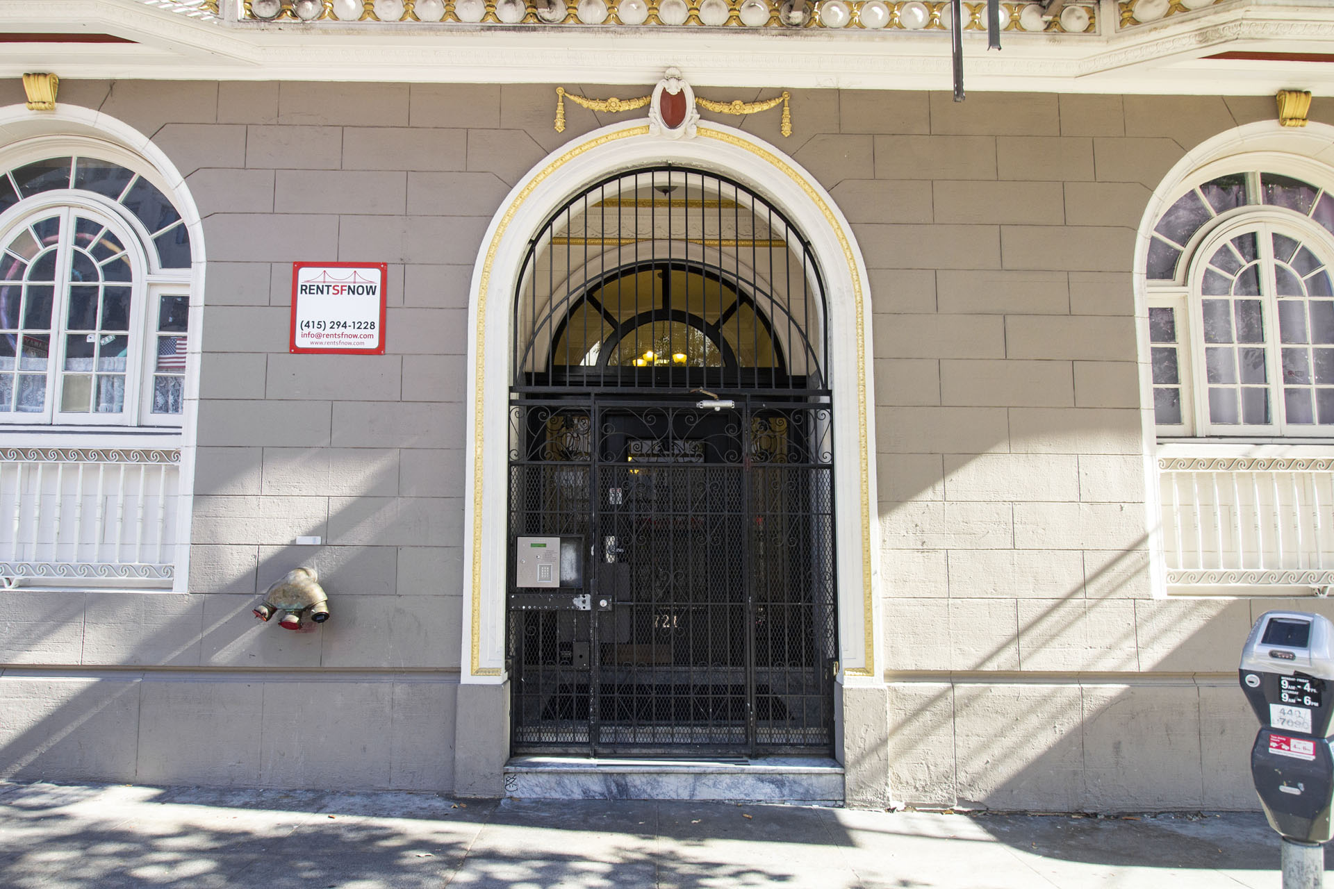 A building with a black gate and a red and white sign on the wall.