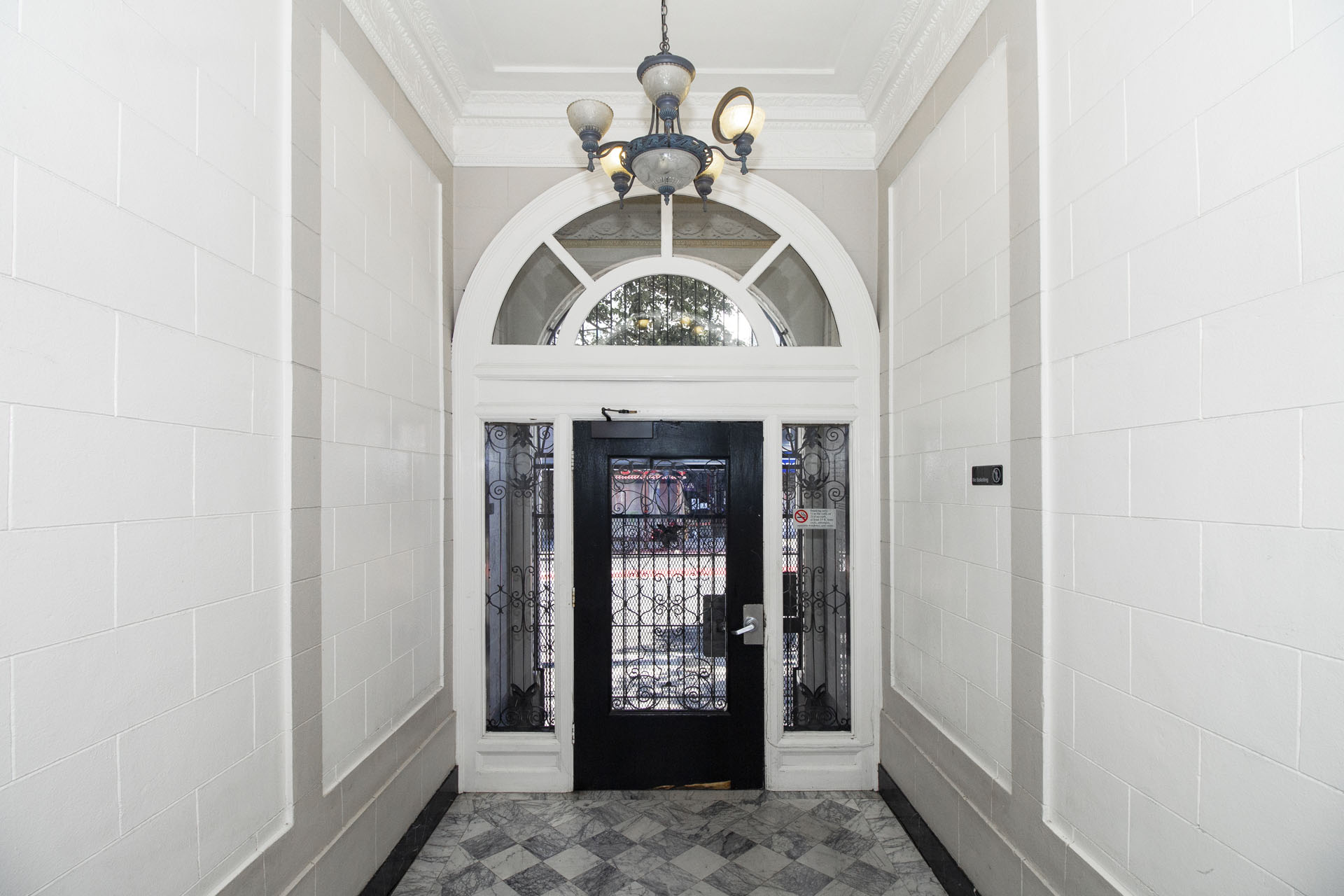 A black door is at the end of a hallway with white walls.