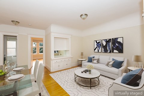 A modern living room with a glass dining table and white couch.