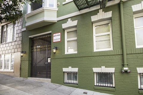 A green building with a black gate and a sign that says "Residential".