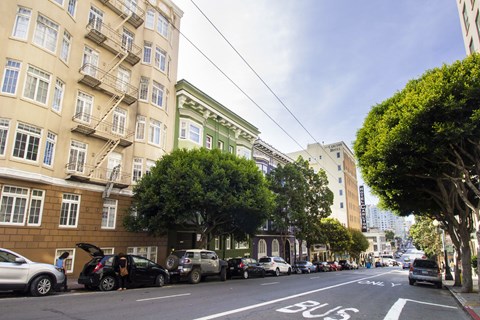 A street with a bus lane and cars parked on the side.