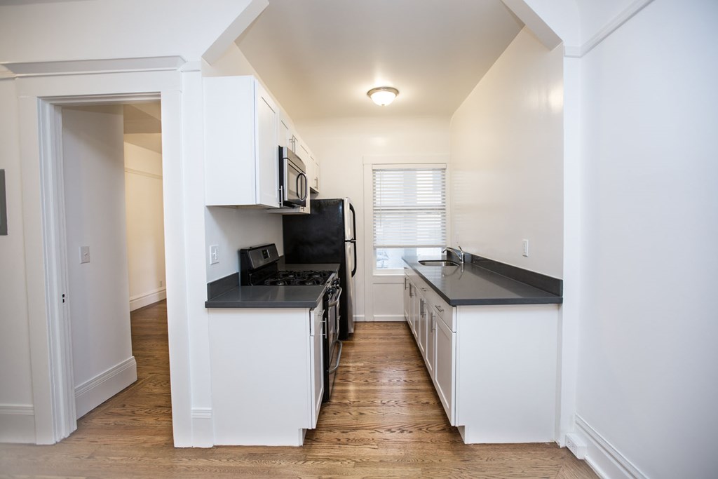 a renovated kitchen with white cabinets and black counter tops