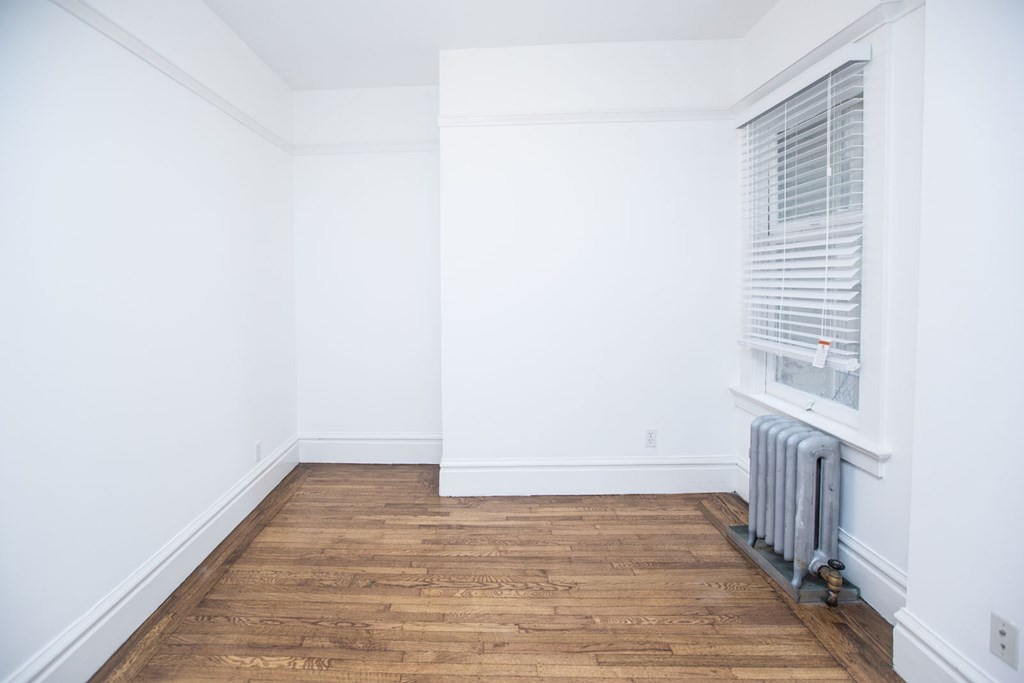 a room with white walls and a radiator and a window