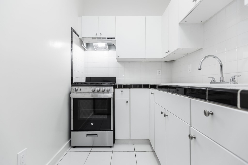A modern kitchen with white cabinets and a stainless steel oven.