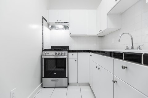 A modern kitchen with white cabinets and a stainless steel oven.