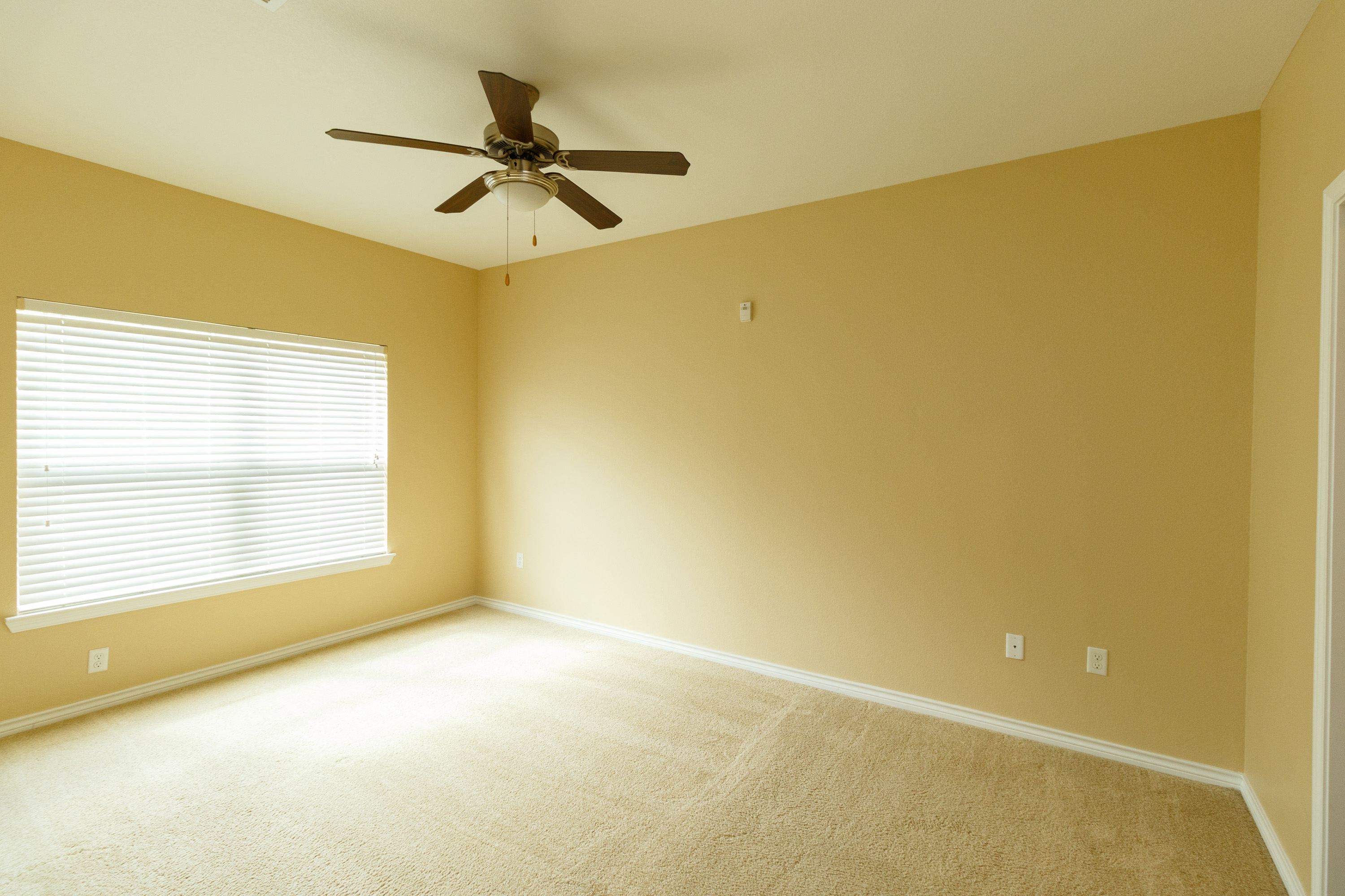 an empty room with a ceiling fan and a window