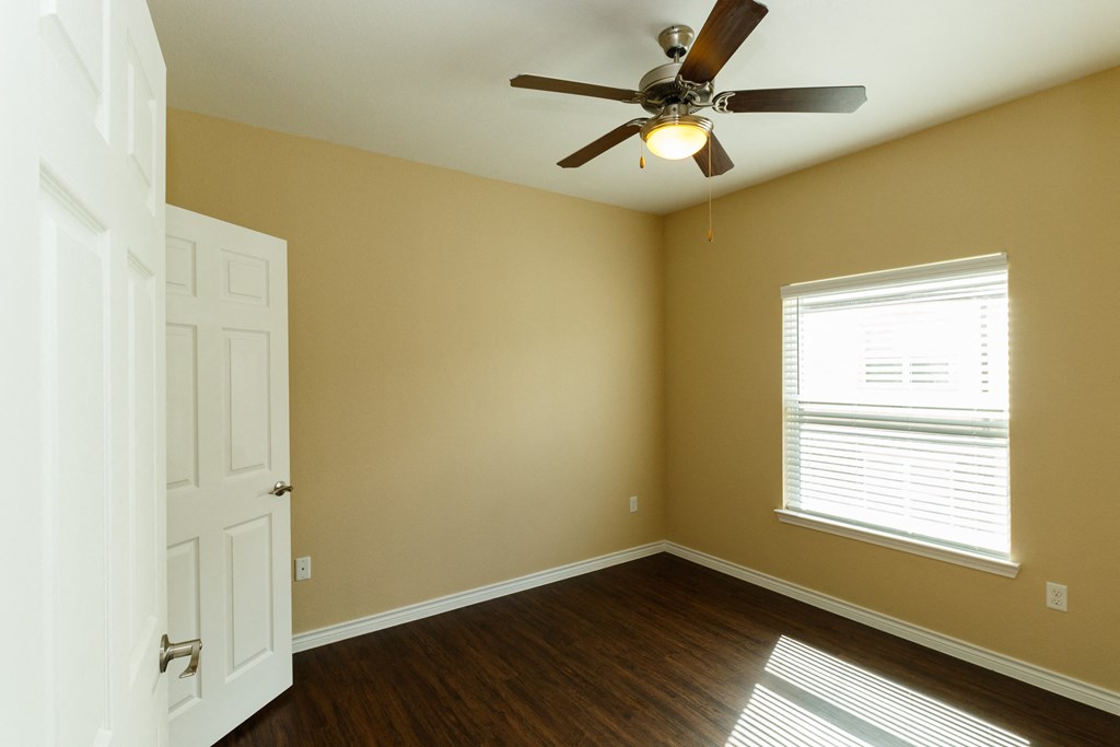 an empty room with a ceiling fan and a window