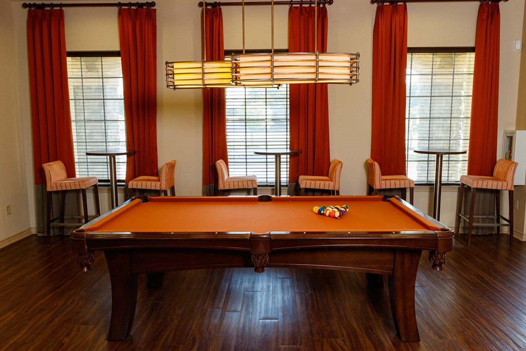 a pool table in a room with chairs and a lamp