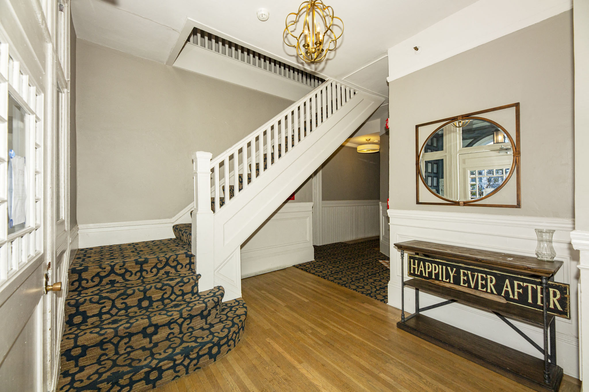A staircase with a black and white carpet and a wooden banister.