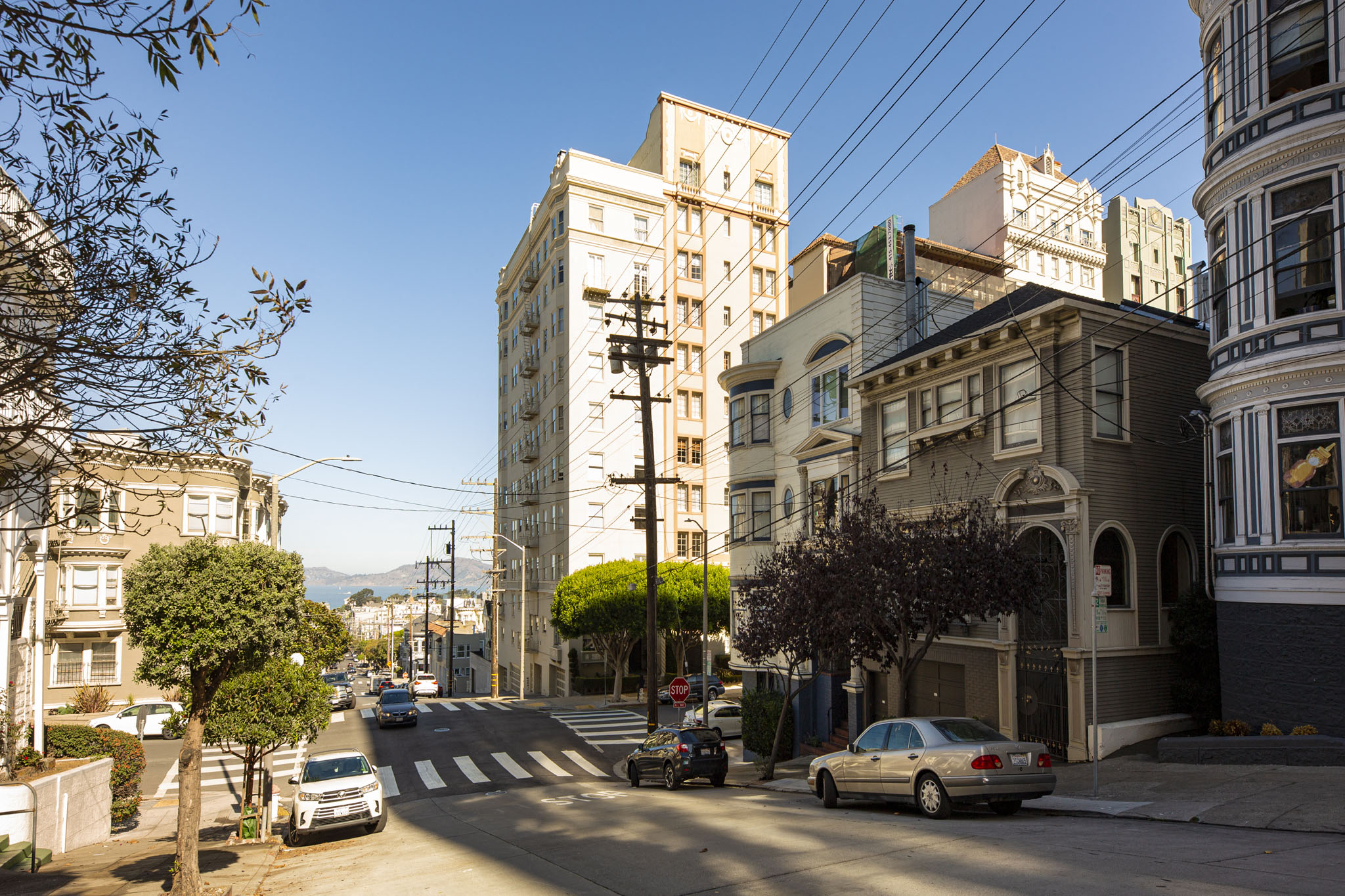 A street view of a residential area with cars parked on the side of the road.