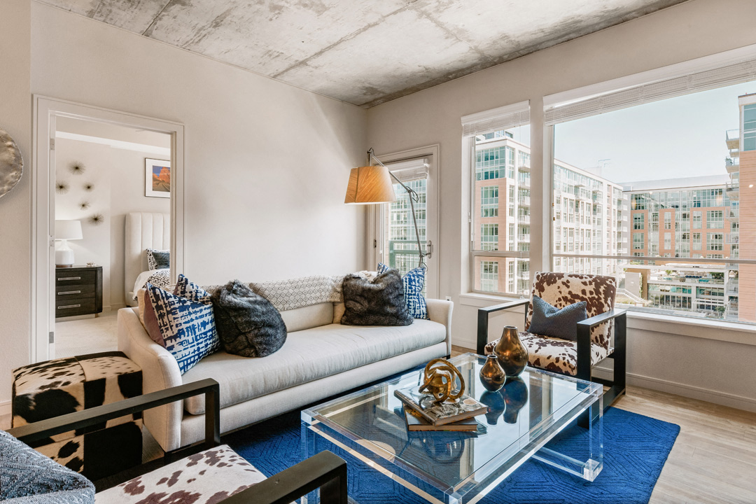 a living room with a couch and a glass coffee table and large windows