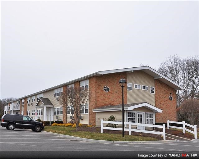 A black SUV is parked in front of a brick apartment building.