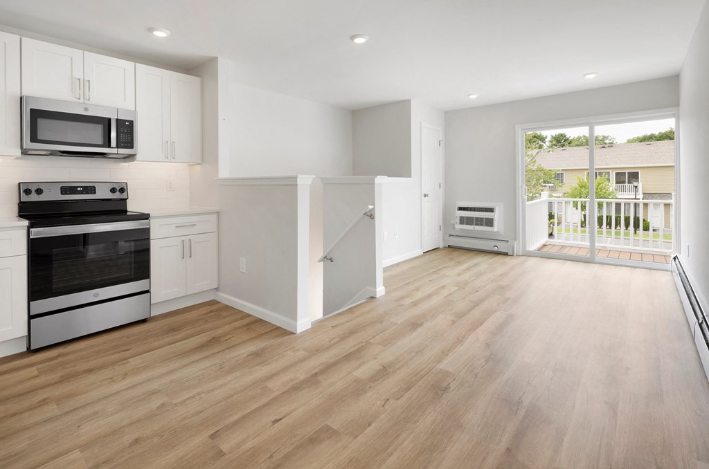 an empty kitchen with white cabinets and a door to a balcony