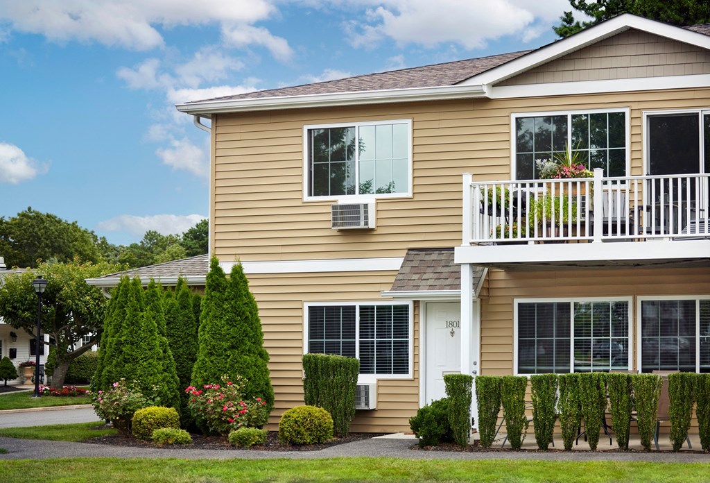 a yellow house with a balcony and a yard