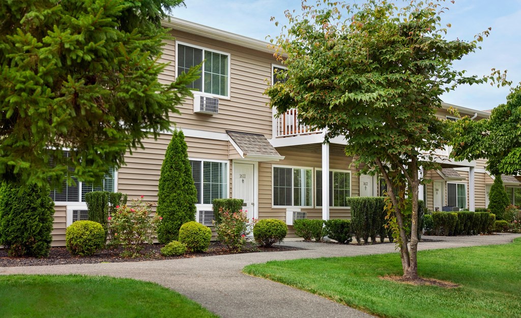 a home with a walkway and trees in front of it