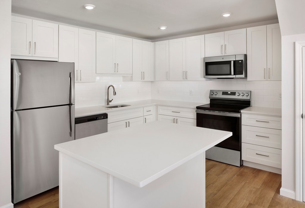 a white kitchen with stainless steel appliances and a white counter top