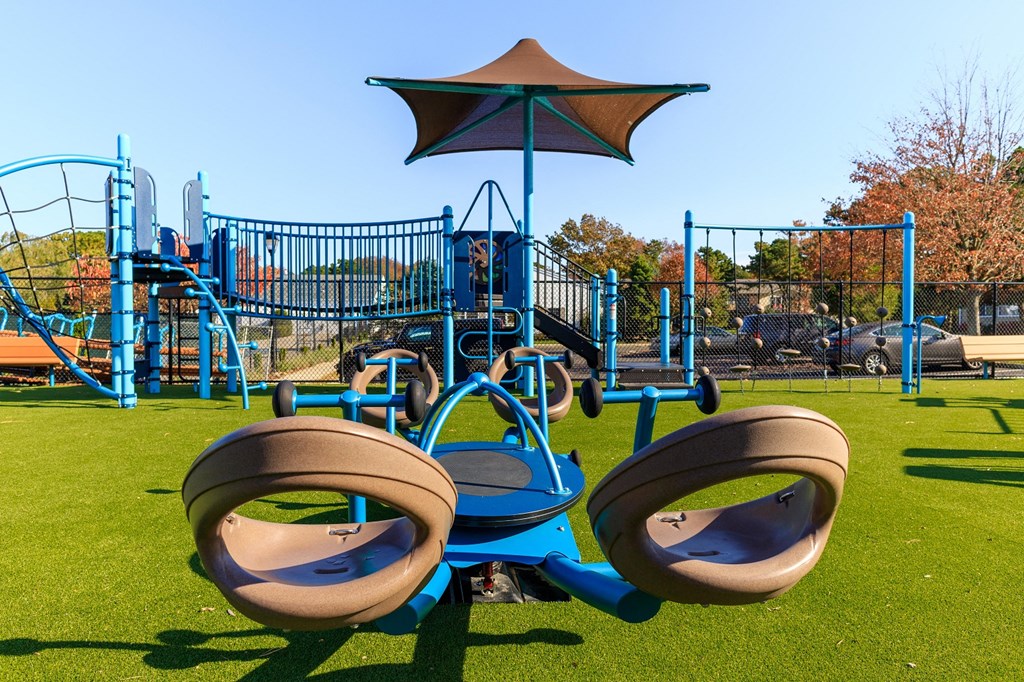 a playground with a blue swing set and an umbrella