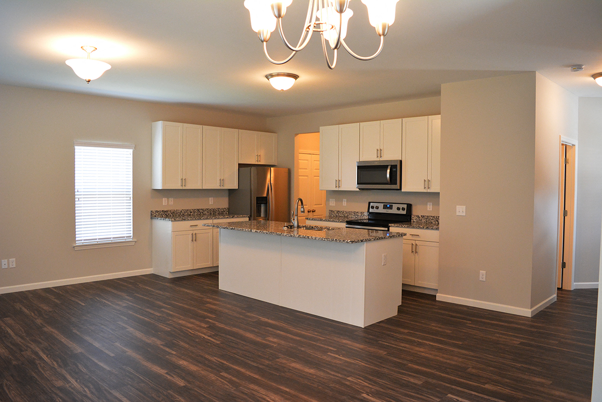a kitchen with white cabinets and a marble counter top