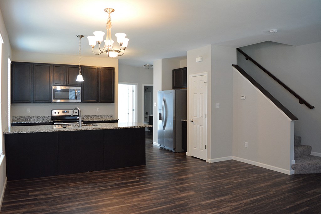 an empty living room with a kitchen and stairs