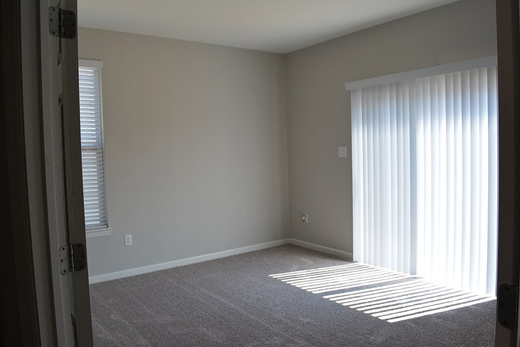 an empty living room with blinds and a window