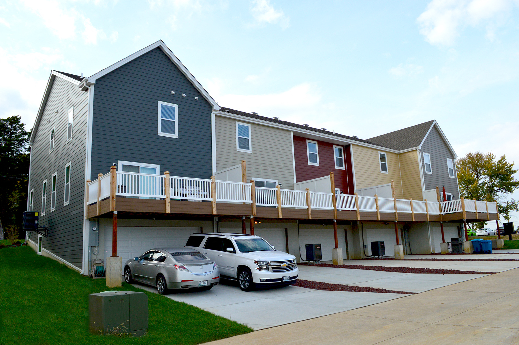 a large house with a deck and cars parked in front of it