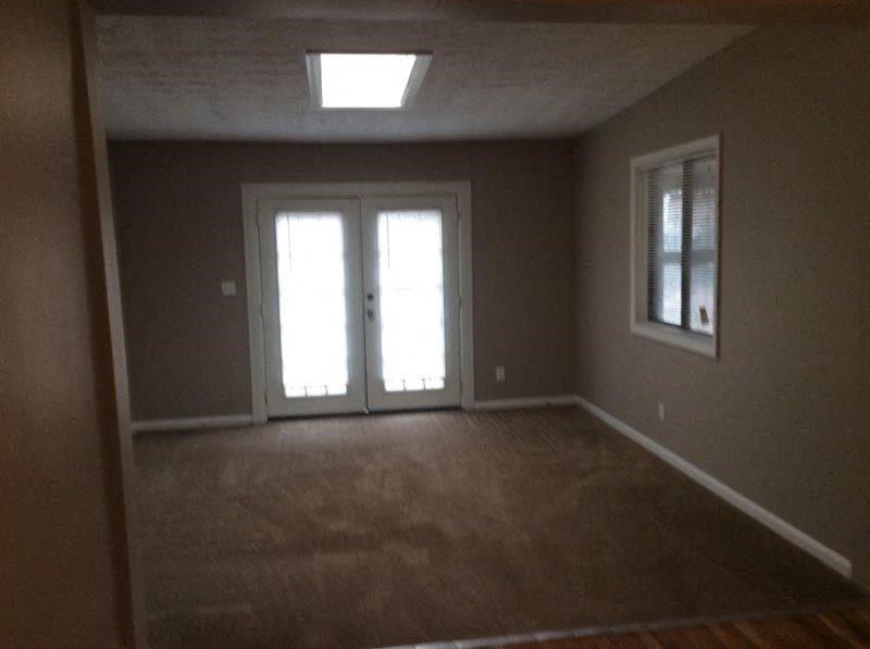 an empty living room with a window and a door