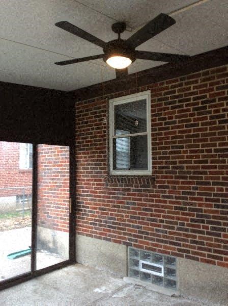 a living room with a brick wall and a ceiling fan