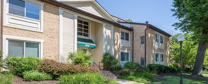 A building with a green awning is surrounded by greenery at Potomac Ridge Apartments, Virginia, 22191