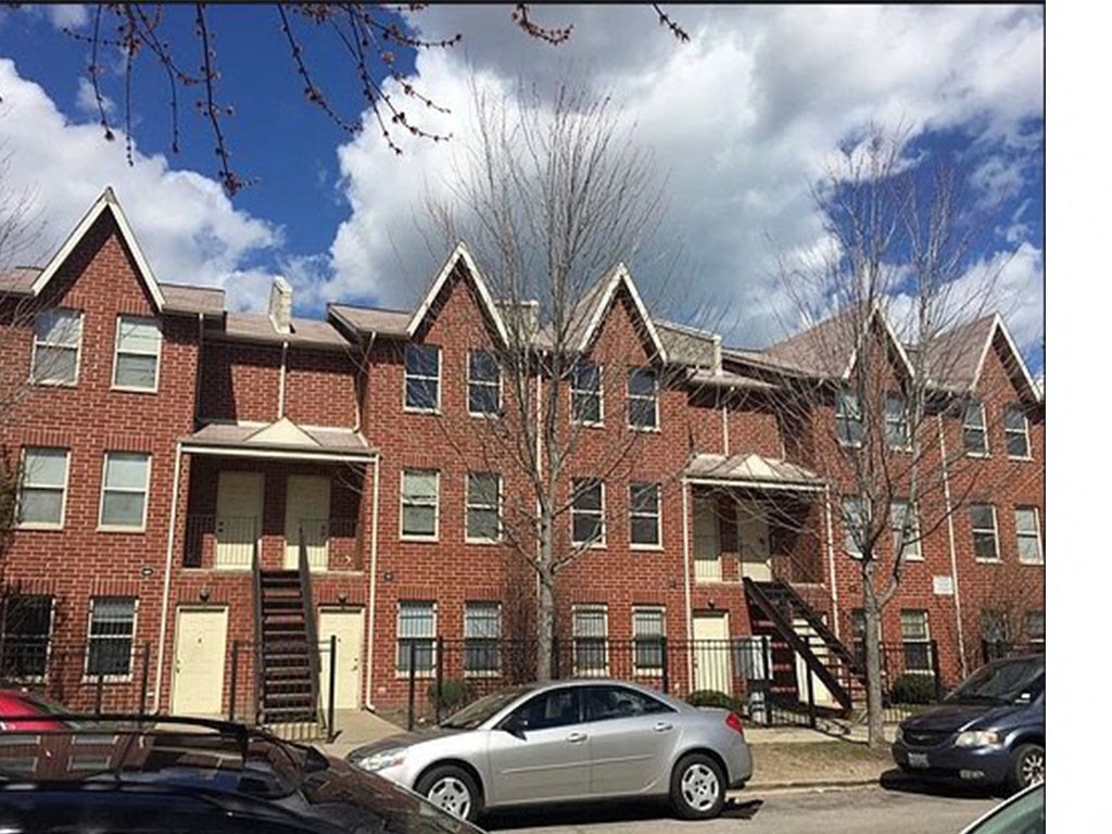 a row of brick apartment buildings with cars parked in front