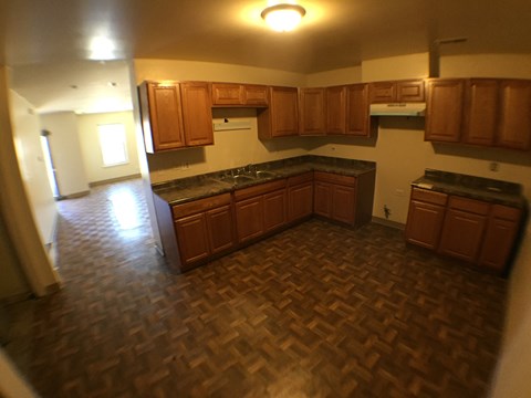 an empty kitchen in an empty house with wood flooring