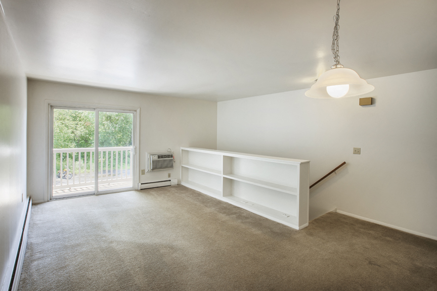 an empty living room with white shelves and a sliding glass door
