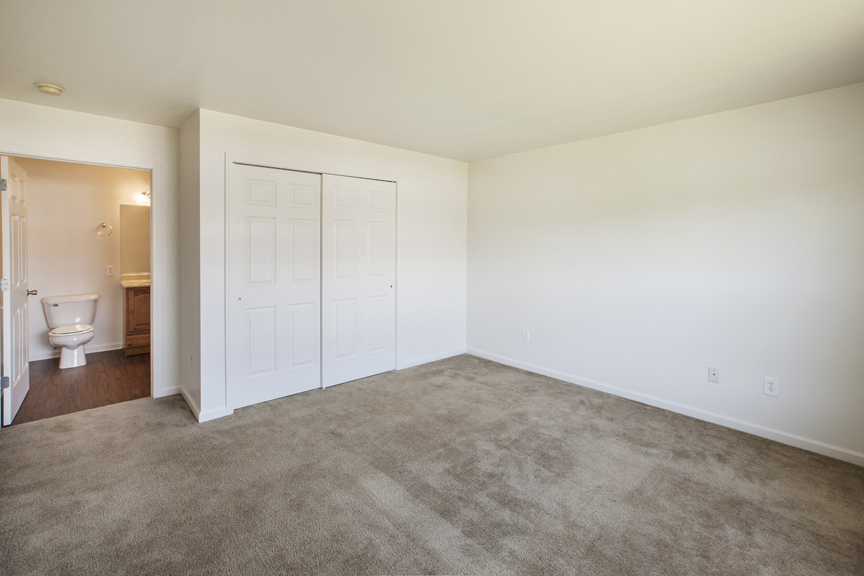 an empty living room with a toilet and a closet