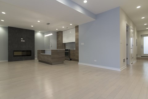 an empty living room with a fireplace and a kitchen