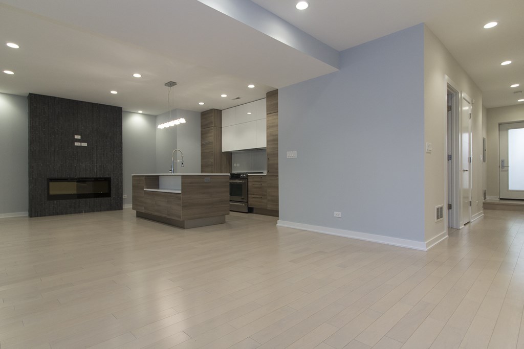 an empty living room with a fireplace and a kitchen